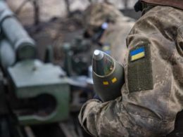 Ukrainian soldiers carry an artillery shell.
