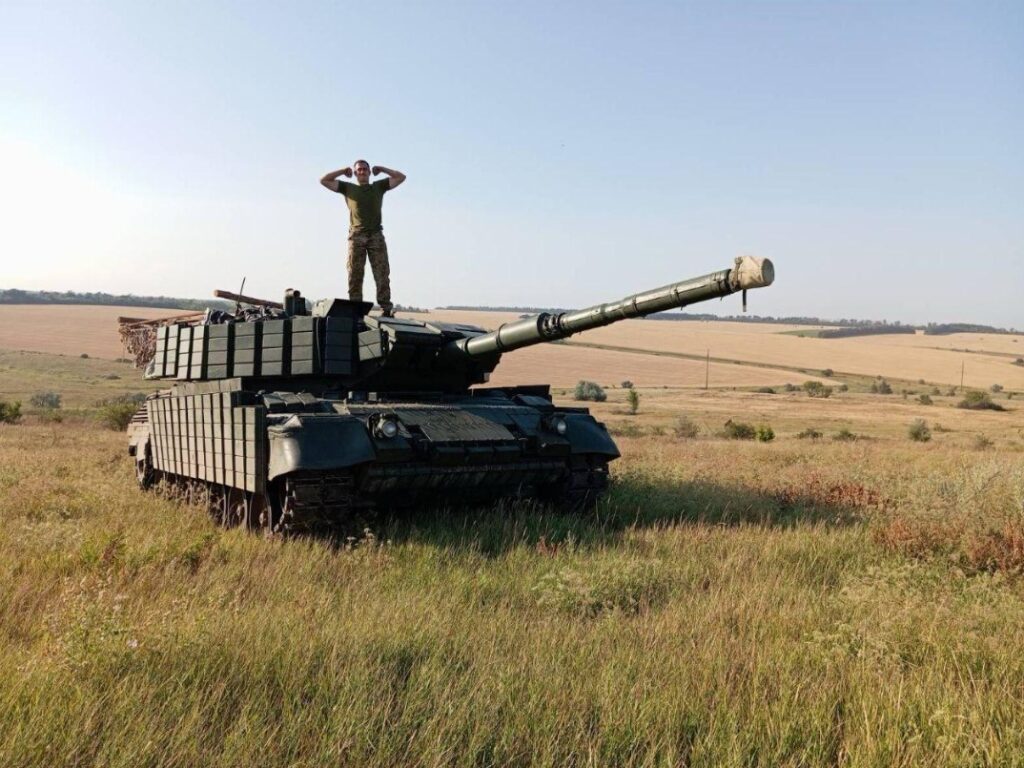 A Ukrainian soldier standing on a Leopard 1A5 tank